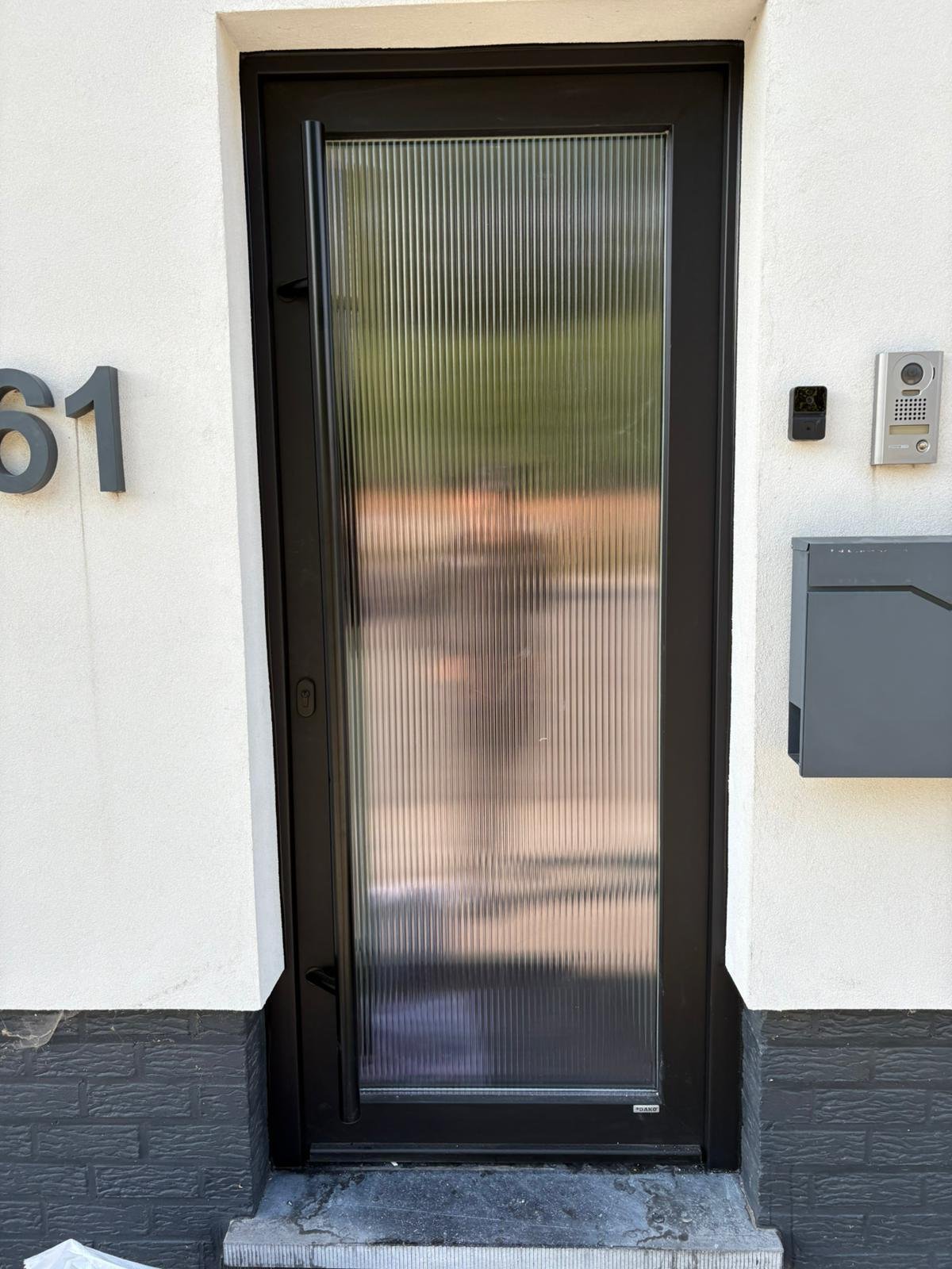 Porte d’entrée vitrée avec encadrement sombre
